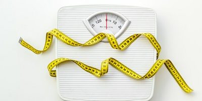 Diet concept with scale and measuring tape for weight loss on white background top view