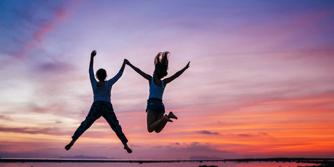 Two running and jumping girlfriends on the sunset sea beach. Han